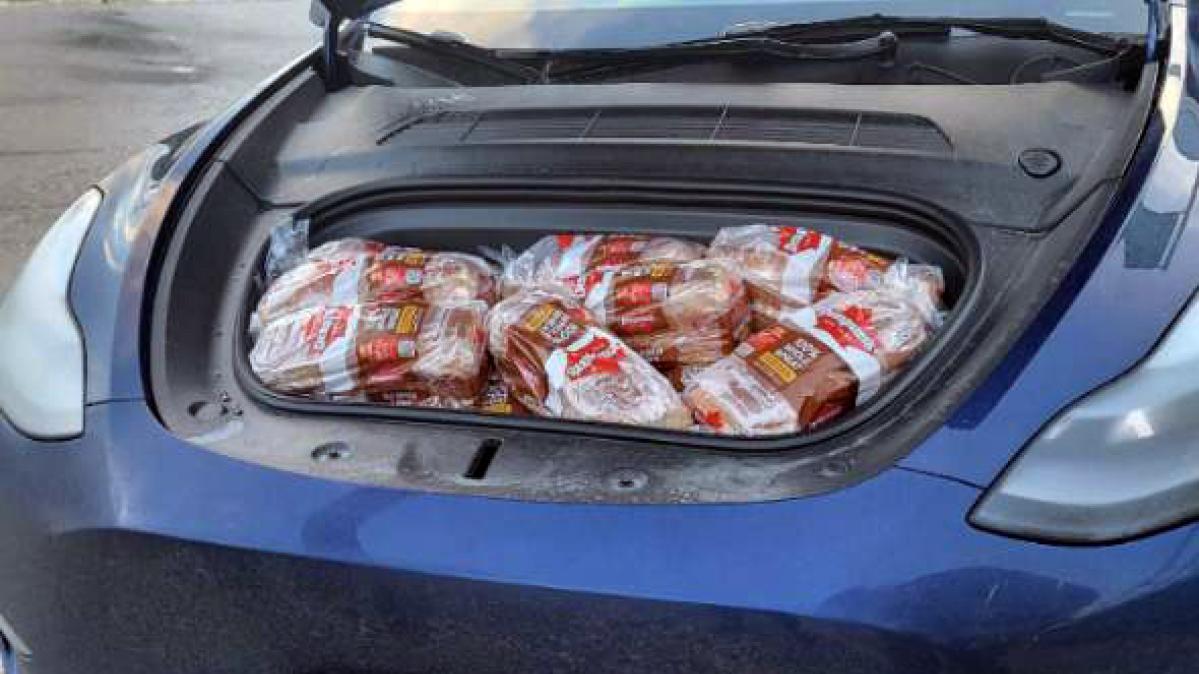 A blue Tesla front trunk full of loaves of whole wheat bread