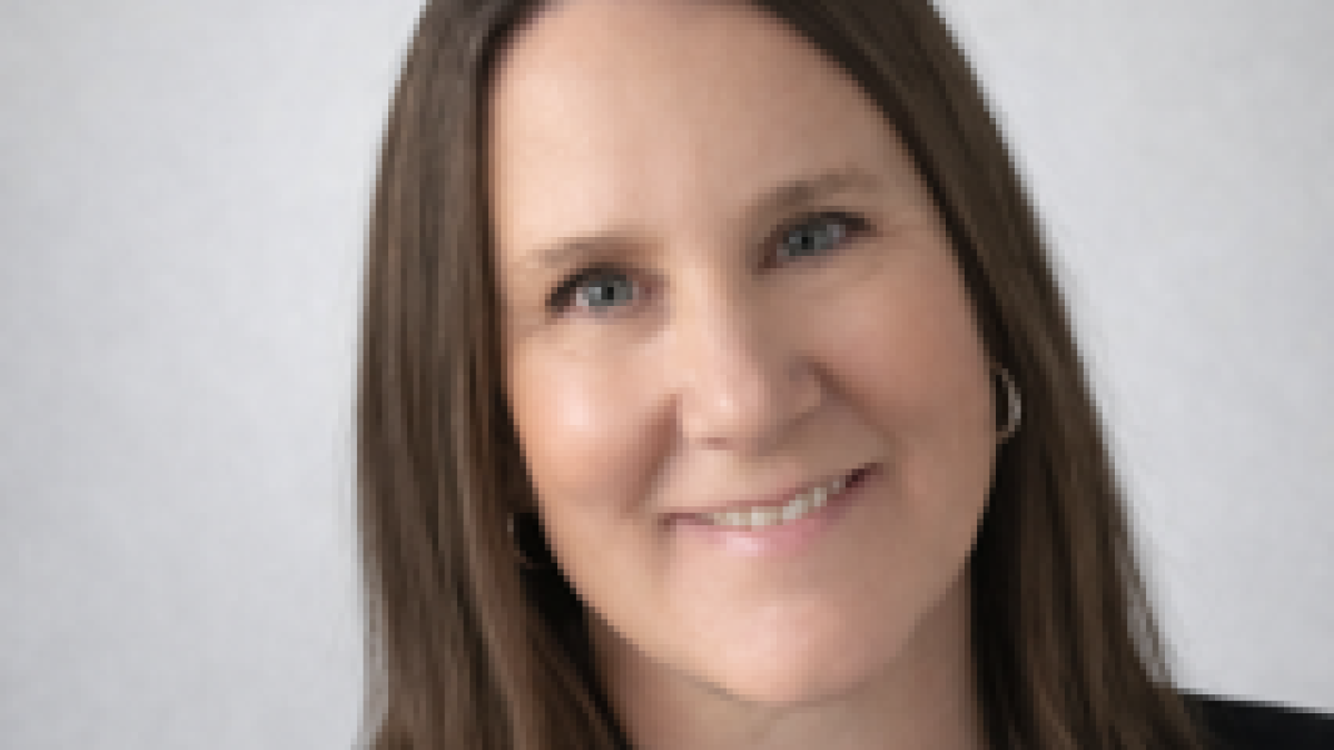 A woman with shoulder-length brown hair wearing a black blazer and white button-up shirt.