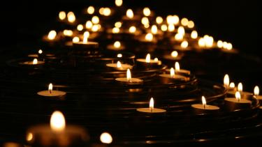 Holocaust Remembrance A scene of darkness with tea candles burning in a long curving line into the night