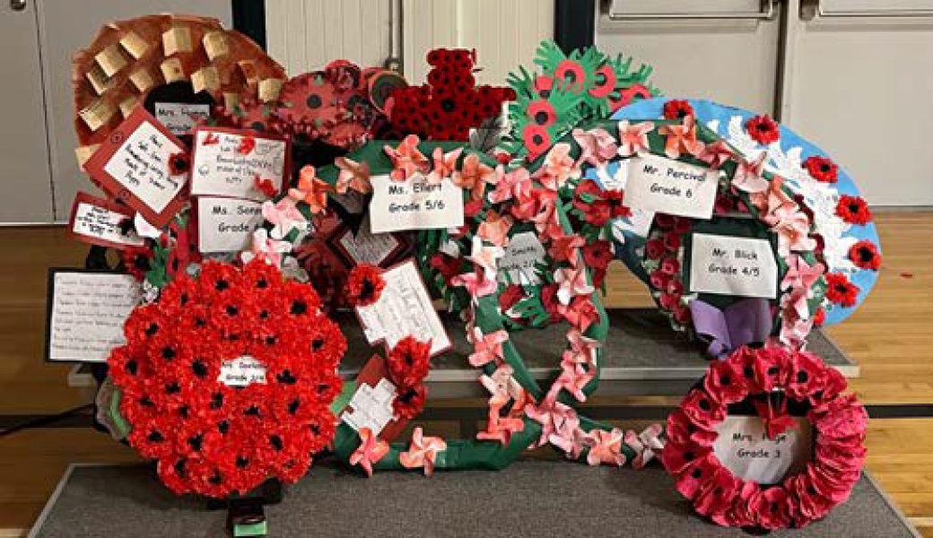 Remembrance Day at ARES Wreaths of red poppies and colourful flowers on grey dais on gymnasium floor