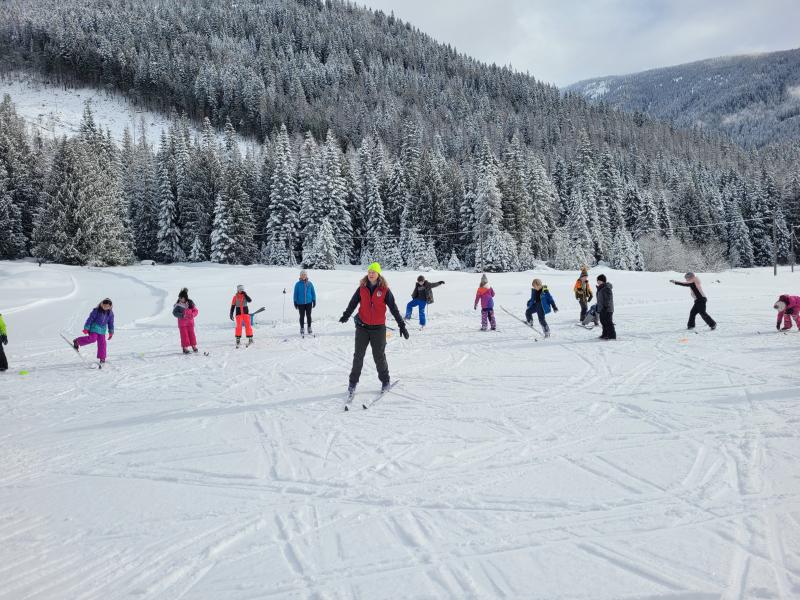 School students in colourful winter outfits skating on a frozen lake in the mountains