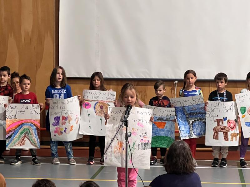 School children wearing large posterboards depicting drawings about the Earth.