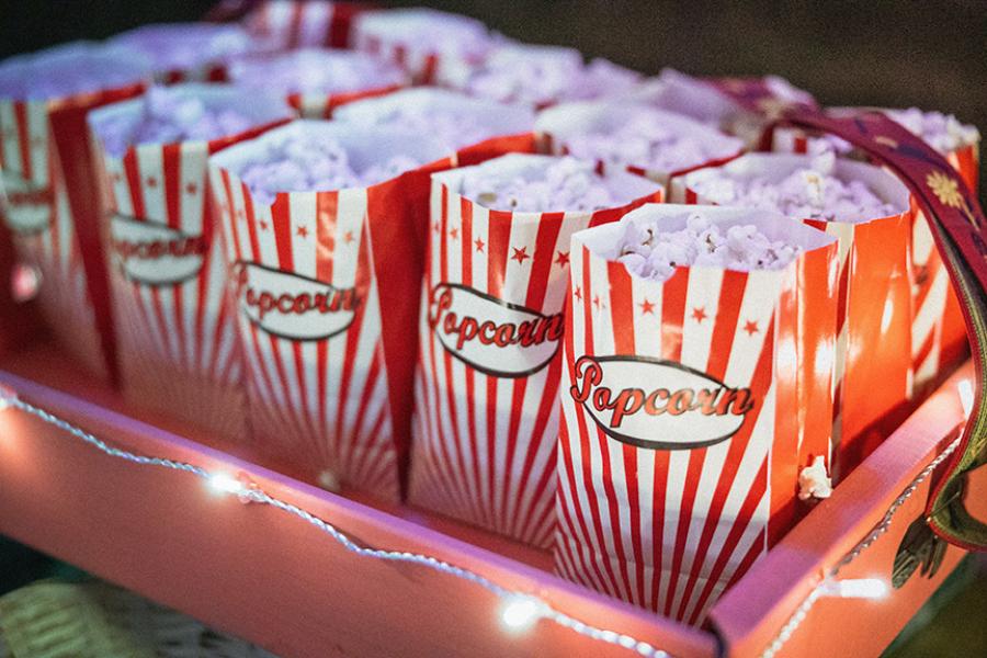 Red tray with lights around it, holding red-striped bags of popped popcorn.