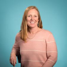 Woman in peach coloured sweater against blue background