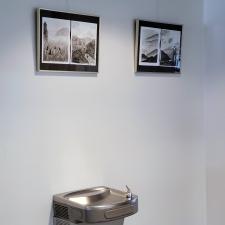 Two monochromatic ink paintings in black frames against a white wall. 