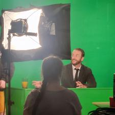 A man against a green screen in front of a bright light.