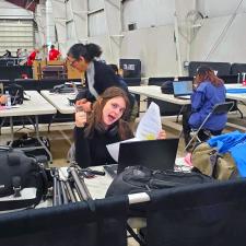 Young woman working at a laptop gives thumbs up