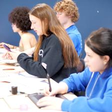 Students at a long table working on digital arts projects